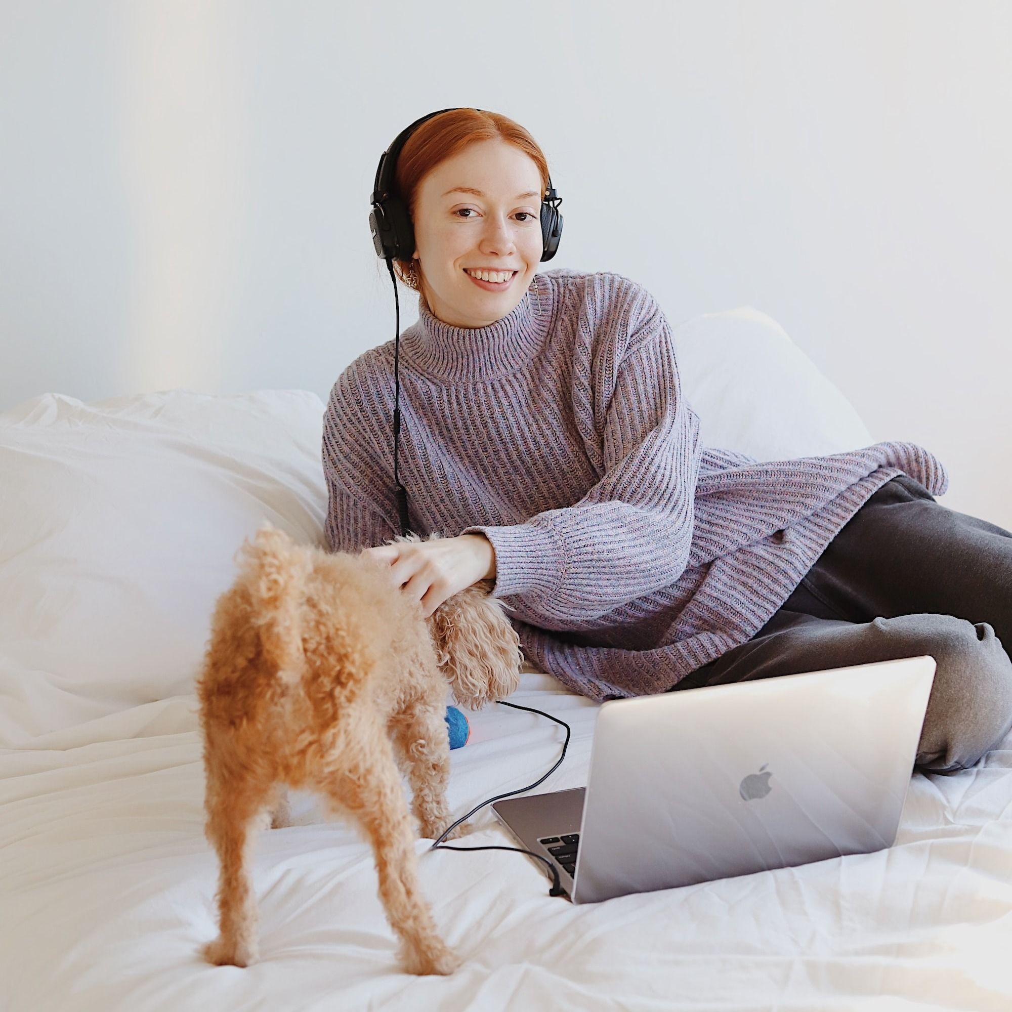 woman in gray and white striped long sleeve shirt and black pants sitting on white bed